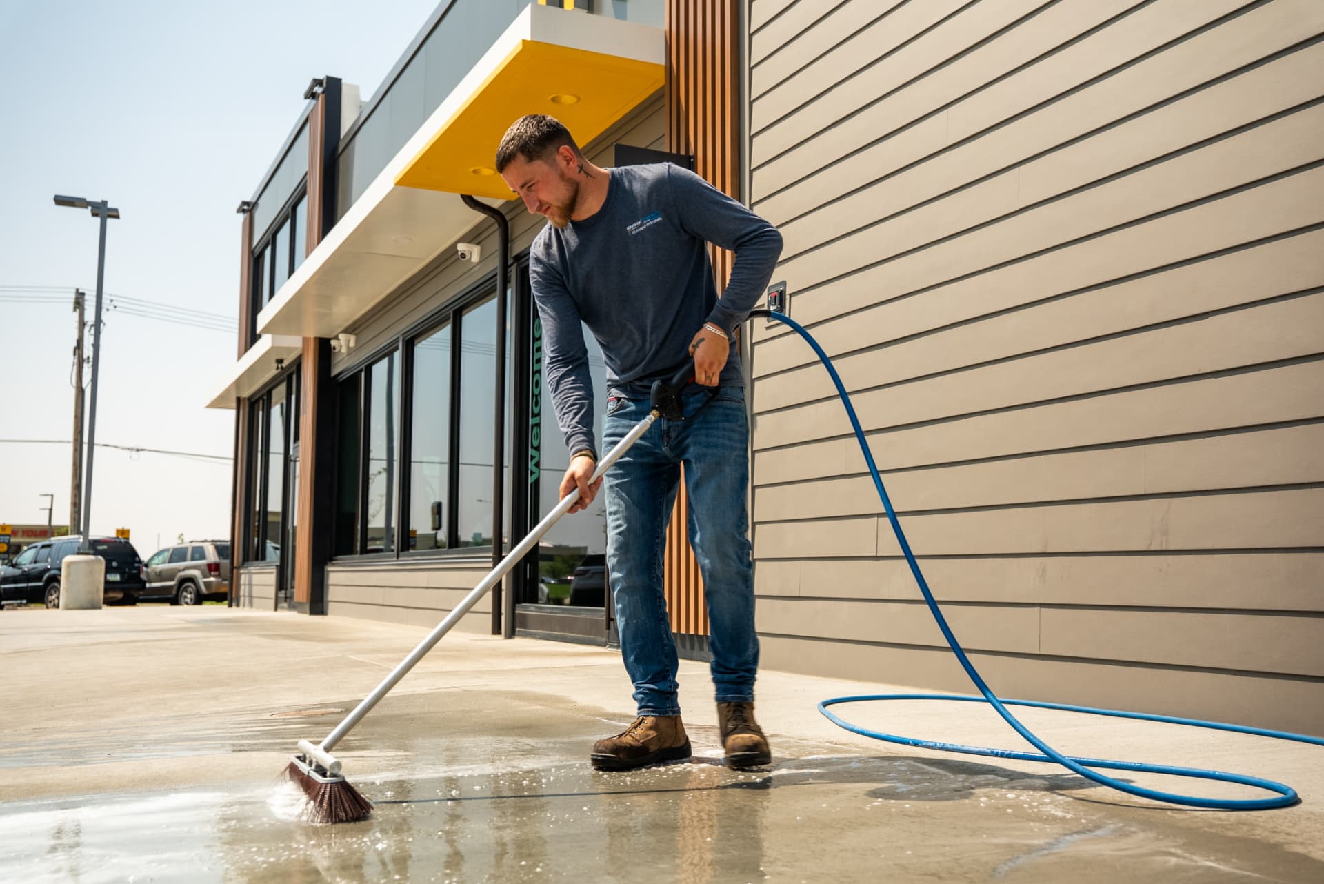 Technician scrubbing a restaurant walkway with an Easiwash brush and hose