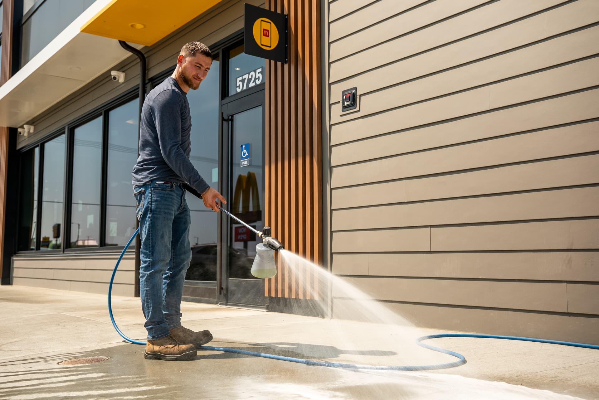 Technician rinsing restaurant siding with an Easiwash foam cannon
