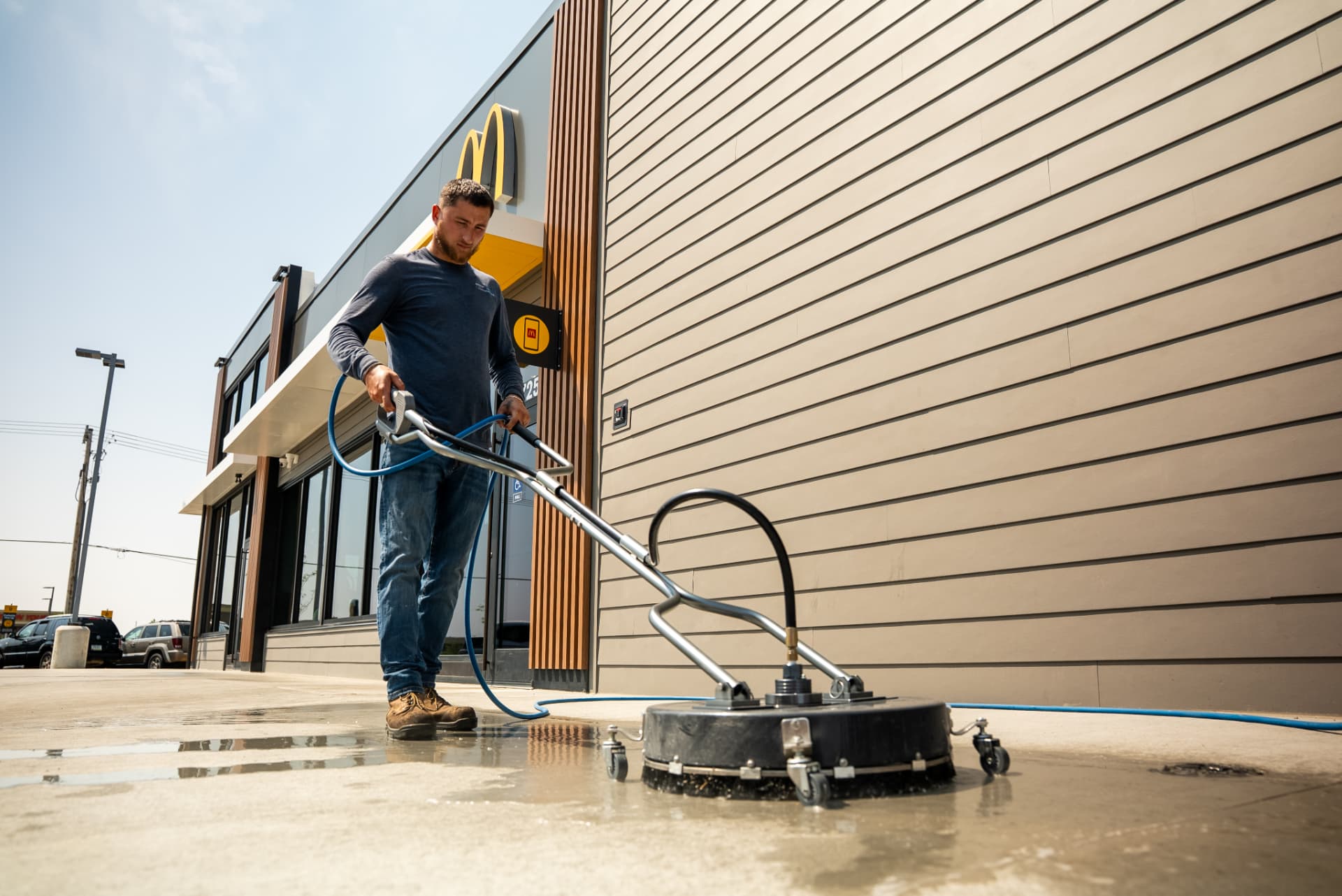 Technician using an Easiwash surface cleaner on a restaurant sidewalk